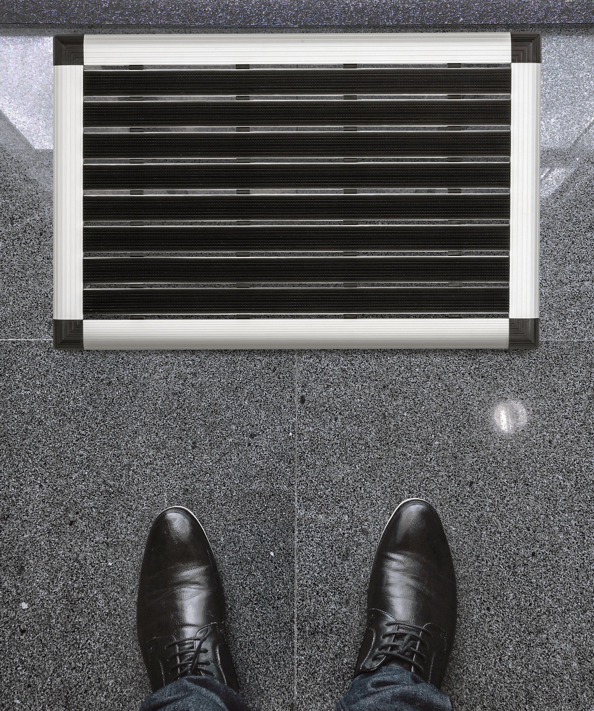 Lifestyle image of Hometex Premium Aluminium Outdoor Entrance Mat by an entrance, featuring shoes for scale and context