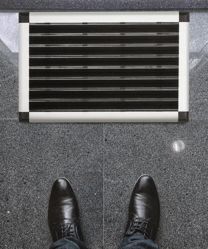 Lifestyle image of Hometex Premium Aluminium Outdoor Entrance Mat by an entrance, featuring shoes for scale and context