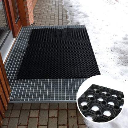 Black textured Hometex All Seasons Outdoor Entrance Mat on a tiled floor with snow outside, close-up of mat pattern shown.