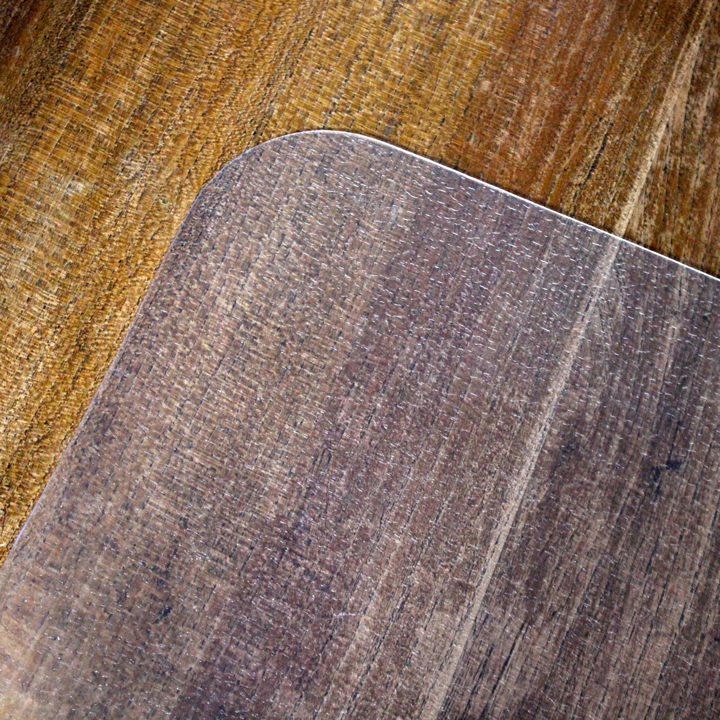 Close-up lifestyle image of the corner of the Universal Floor Protector on a hardwood floor.